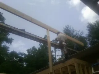 Carpenter setting a ridge beam over a new addition frame — Ice Dam Removal by Roofing Brothers in Winston-Salem