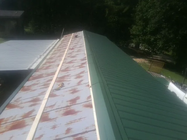 Old rusted panels beside newly installed green metal roofing — Wind Damage Roof Repair by Roofing Brothers in Winston-Salem