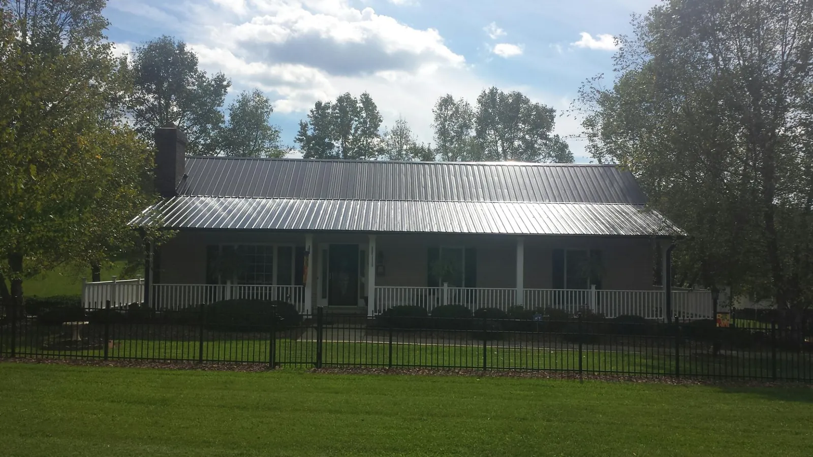 Gray metal roof on a brick ranch with a full width front porch — Gutter Guard Installation work by our crew in Winston-Salem