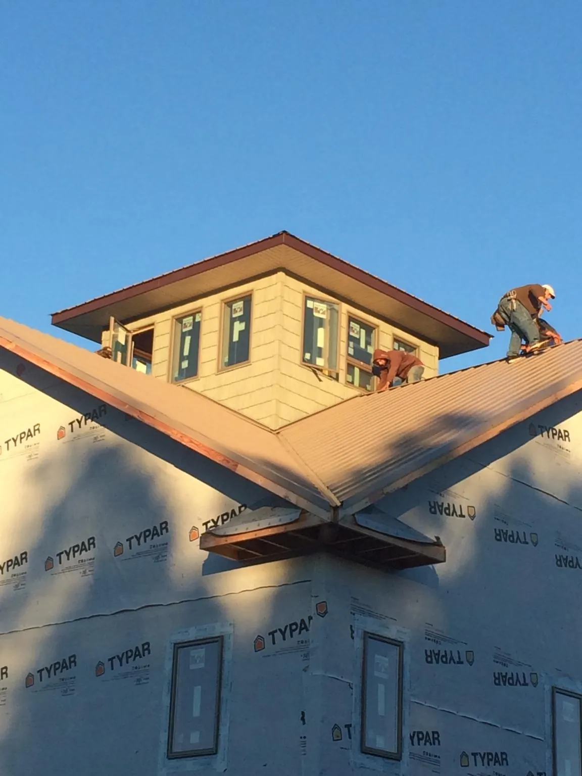 Roofers working around a rooftop cupola on a new metal roof at sunset — Roof Waterproofing in Winston-Salem by Roofing Brothers